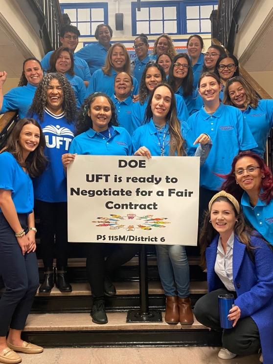 School educators hold up a sign reading "DOE, UFT is ready to negotiate for a fair contract"