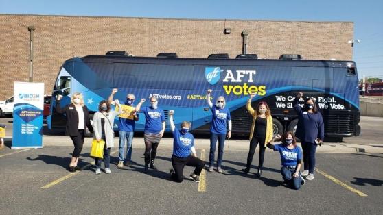 9 members raise their fists in front of a bus during their efforts to get out the vote