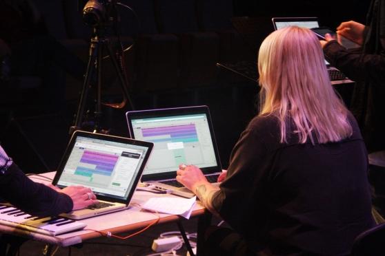 A girl with pink hair works on a laptop.
