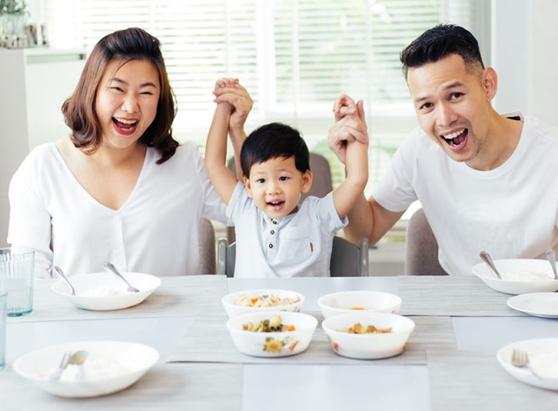 Asian couple with small child smiling with hands up