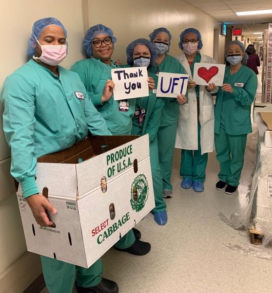 Nurses wearing PPE holding up sign thanking UFT for wrapped lunches