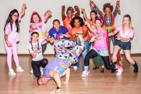 Dance teacher Jennifer Gruet (third from right in pink shirt and bow) and her merry troupe cheer the moves of tech teacher — aka breakdancer — Jake Lederman.