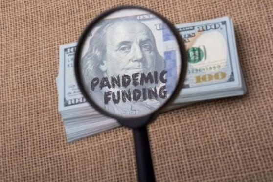 Image of a magnifying glass with the words pandemic funding