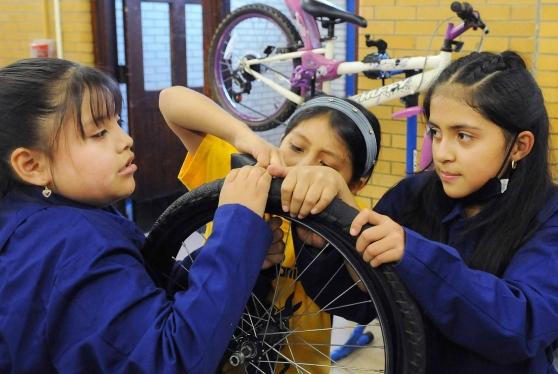 Three girls repair a bike