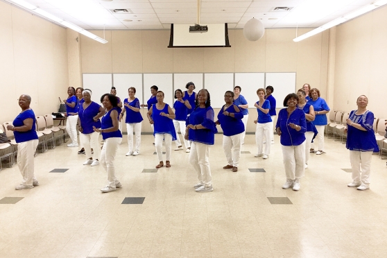 Women in a dance line wearing blue shirts and white pants