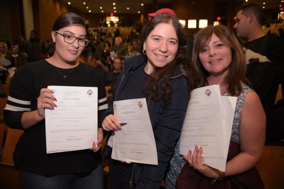 Three smiling women displaying certificates, representing UFT teacher certification