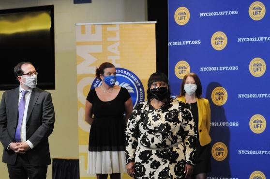Four people standing in front of banners wearing masks