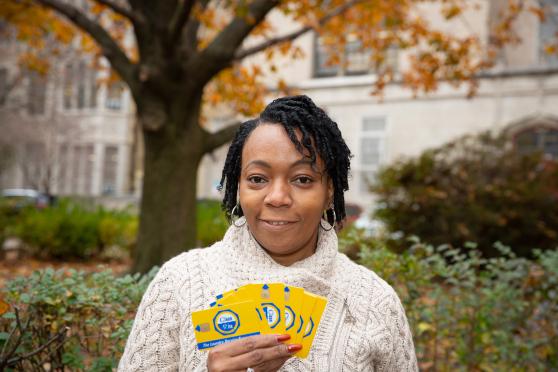 A woman wearing a white sweater holds up laundry cards