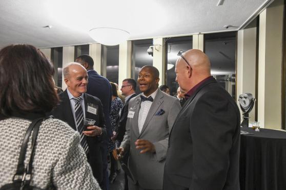 Three men are engaged in a conversation during a conference