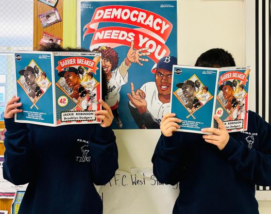 Students hold up a comic book in front of their faces.
