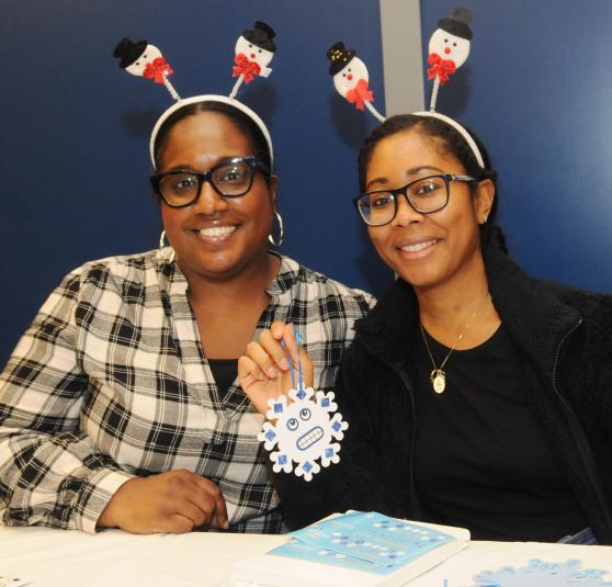 Two teachers smile for a photo while showing off one of their crafts at the UFT/Coalition for the Homeless holiday toy drive and celebration on Dec. 7, 2024. 