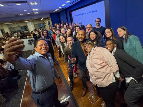 Social Worker and Psychologists Chapter Leader Raul Garcia takes a group selfie with UFT members on stage.