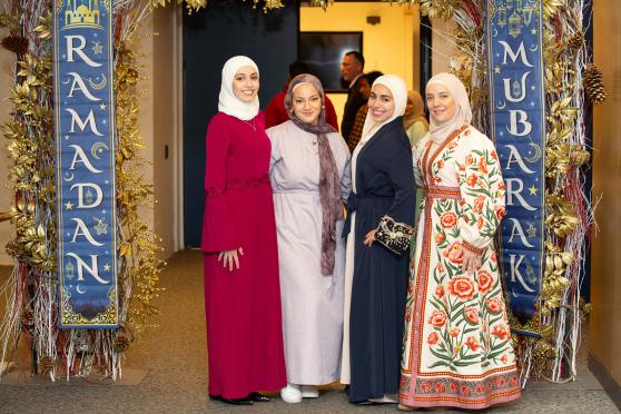 Teachers attending the UFT Muslim Educators Committee Iftar Dinner on March 7, 2025 pose between banners reading “Ramadan Mubarak,” which means “Blessed Ramadan.”