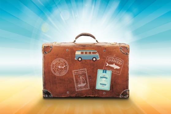 Old fashion style suitcase covered in travel stickers and a 70's van