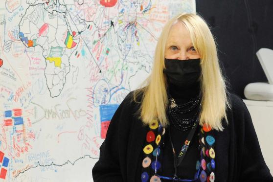 A woman poses in front of a drawing of a map 