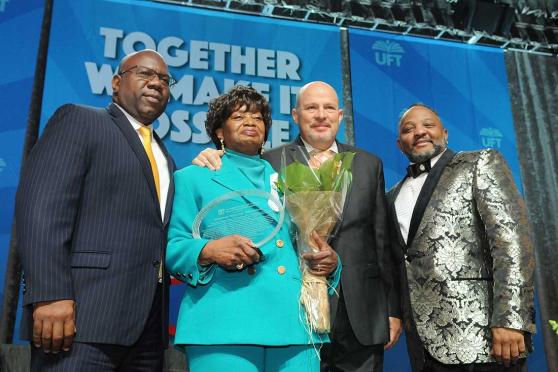 Four people pose for a photo and one is holding an award. 