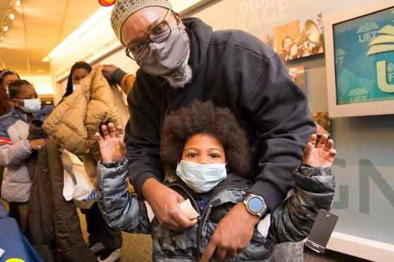 UFT District 9 Representative Aqeel Williams helps a boy try on his new coat. 