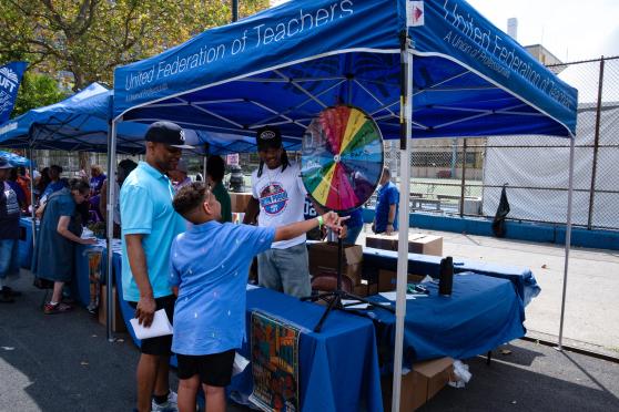 Families line up at the UFT booth during Harlem week festivities.