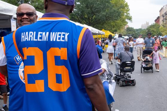 A man wearing a basketball jersey where the back reads "Harlem Week 26". 