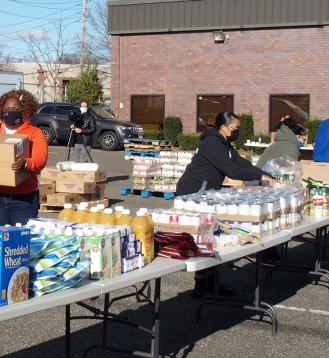 Woman carrying boxes while other people load them